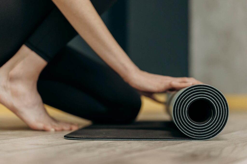 krachtsport accessoires shop woman rolling a yoga mat
